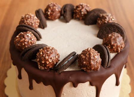 Handmade chocolate cake on wooden background. Chocolate cake decorated with chocolate, sweets and biscuits.の写真素材