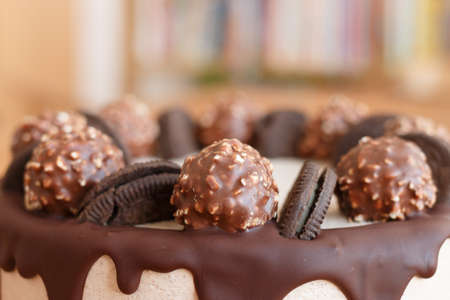 Handmade chocolate cake on wooden background. Chocolate cake decorated with chocolate, sweets and biscuits.の写真素材