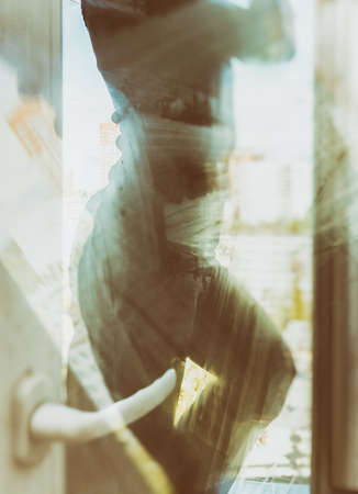 A young woman washes a window at home. Reflections, glare, light in the windows. General house cleaning. Window cleaning. Spring-cleaning.の写真素材