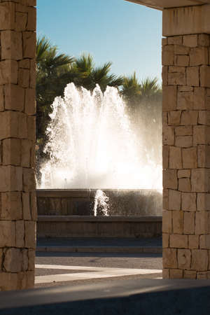 Fountain in the European city. View of the fountain through the colonnade of the historic building.の写真素材