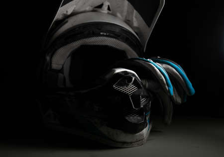 Motocross helmet and gloves. Dirty motocross helmet. Moto equipment. Conceptual photograph of a motorcycle helmet. Tragic mood.の写真素材