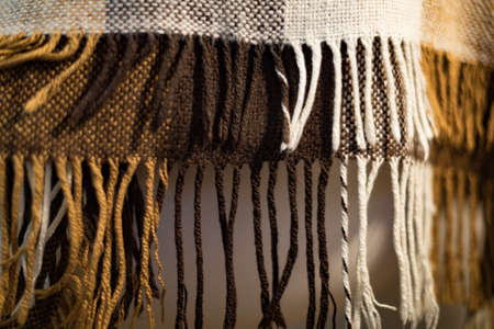 Checkered brown and white plaid with fringe. Woolen checkered plaid. Plaid photographed with shallow...