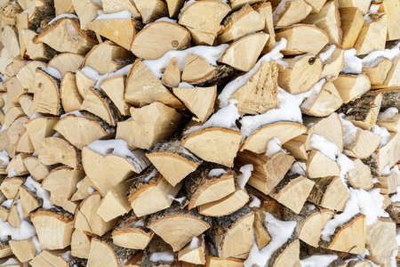 Firewood in woodpile for the winter. Pile of firewood. The firewood background. A stack of neatly stacked firewood on the street with snow.の写真素材