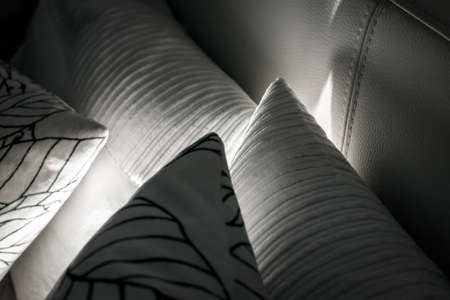 Pillows on the bed with night lights. White cushions with a pattern and different texture. Decorative pillows on the bed with leather back.の写真素材