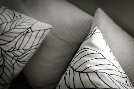 Pillows on the bed with night lights. White cushions with a pattern and different texture. Decorative pillows on the bed with leather back.の写真素材