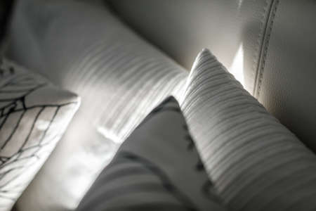 Pillows on the bed with night lights. White cushions with a pattern and different texture. Decorative pillows on the bed with leather back.の写真素材