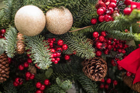 Decorated Christmas tree. Bright decorations for the New Year. Christmas decoration. Gold balls, red berries and ribbons, cones decorate the Christmas tree. Christmas decoration. Background for New Year's greetings.の写真素材