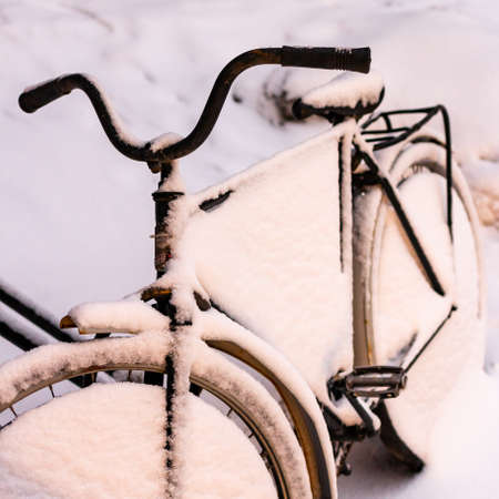 Snow covered old bike in the bicycle parking. Winter in the city streets. Snowy weather. Old classic bike on the street in winterの写真素材