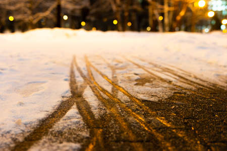 Creative abstract background from the set of traces of human foot prints and the wheels of baby carriage in the snow. Footprint in the snow. Snowy path in the park. Snowy weather in the city.の写真素材