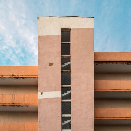 The wall of an old industrial building. Industrial background. A wall of blocks, panels and bricks. Old multi-level parking. Soviet architecture. Colorful architectural background. Wall of various building materialsの写真素材