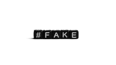 Black letter beads with hashtag and word fake on white background. Fake news and propaganda conceptの写真素材