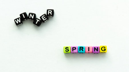 Spring coming and changing winter. Spring concept. Colorful letter beads on white background.の写真素材