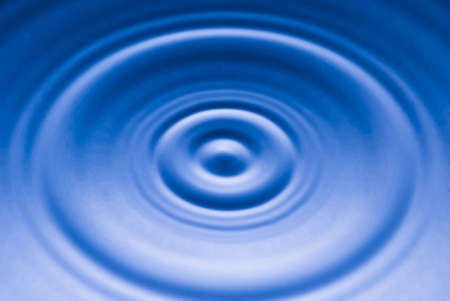 circular waves produced by a falling droplet on a blue water surface