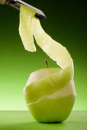 partially peeled green apple on green board isolated on graduated green background の写真素材