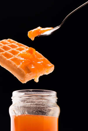 apricot jam in glass jar, Belgian waffle and tea spoon composition