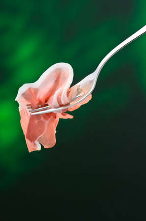 Slice of raw ham on a forkの写真素材