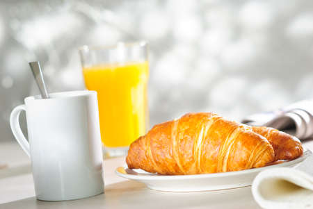 breakfast croissant, glass of orange juice and cup of hot drink