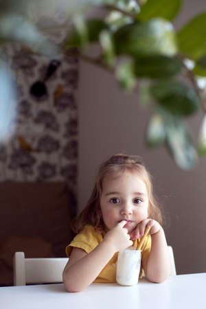 Cheerful little girl eating plain homemade yogurt using spoon. Healthy smiling kid, organic natural foodの写真素材