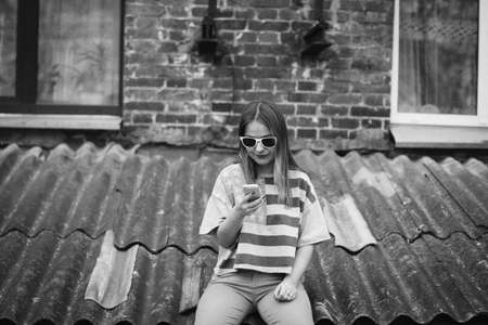 Hipster girl in the old courtyard with phoneの写真素材