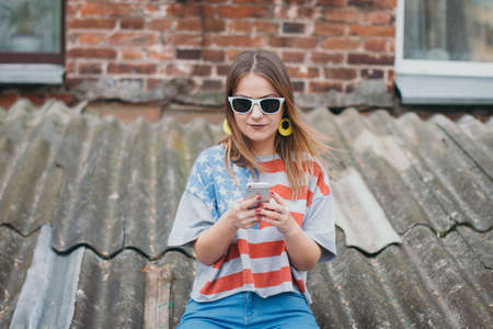 Hipster girl in the old courtyard with phoneの写真素材