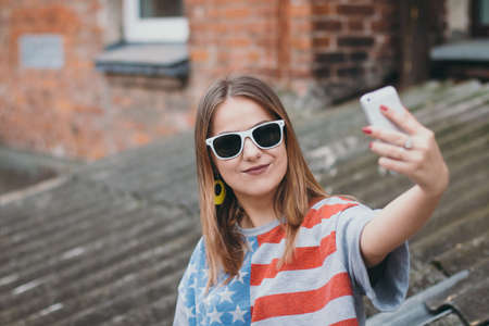 A hippest girl in an old courtyard with a phone makes a selfieの写真素材