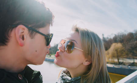 Beautiful loving each other couple is standing on the bridge smiling and kissing.の写真素材