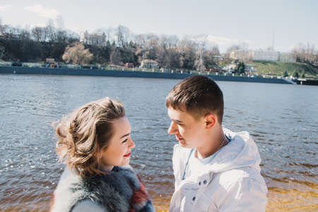 Happy couple in love hugging and sharing emotions, holding hands on the river bank