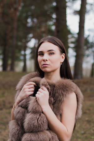 Portrait of a very beautiful girl in a forest dressed in fur