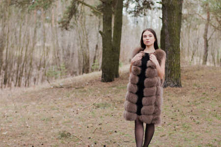 Portrait of a very beautiful girl in a forest dressed in fur