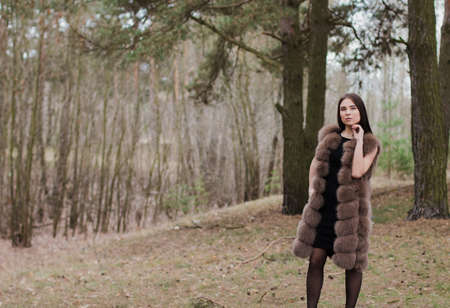 Portrait of a very beautiful girl in a forest dressed in fur