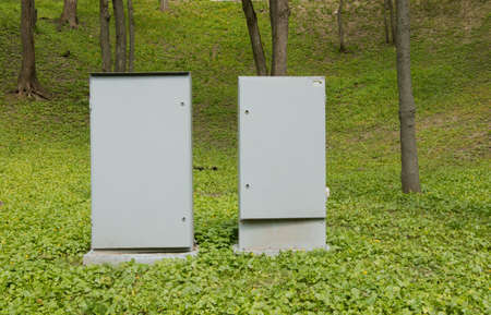 Concrete old weathered distribution box for electricity, metal door, green grass. The concrete box on the meadow. Lonely distribution cabinet.の写真素材