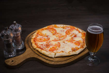 Hot piece of pizza with melted cheese on a rustic wooden table and beer.の写真素材