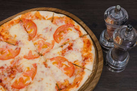 Hot piece of pizza with melted cheese on a rustic wooden table.の写真素材