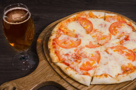 Hot piece of pizza with melted cheese on a rustic wooden table.の写真素材