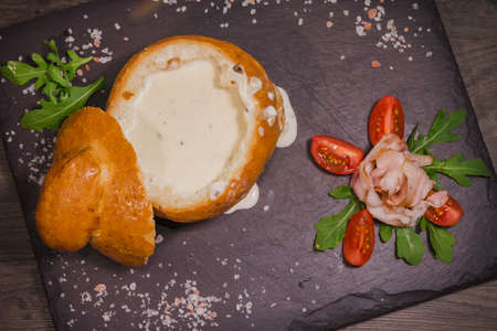 Fresh pea soup in a Bread Bowl, on a wooden board with salt and papper.の写真素材