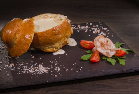 Fresh pea soup in a Bread Bowl, on a wooden board with salt and papper.の写真素材