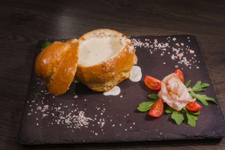 Fresh pea soup in a Bread Bowl, on a wooden board with salt and papper.の写真素材