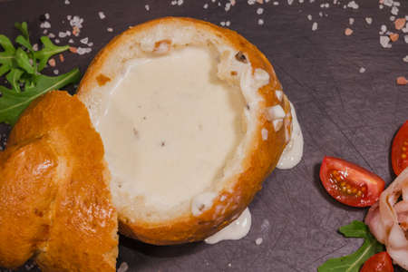 Fresh pea soup in a Bread Bowl, on a wooden board with salt and papper.の写真素材