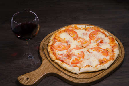 Hot piece of pizza with melted cheese on a rustic wooden table.の写真素材
