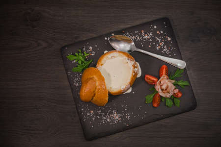 Fresh pea soup in a Bread Bowl, on a wooden board with salt and papper.の写真素材