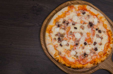 Hot piece of pizza with melted cheese on a rustic wooden table.の写真素材