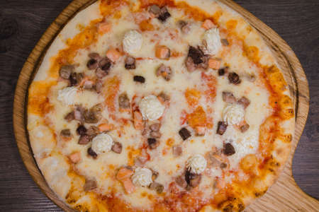 Hot piece of pizza with melted cheese on a rustic wooden table.の写真素材