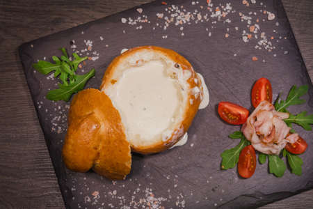 Fresh pea soup in a Bread Bowl, on a wooden board with salt and papper.の写真素材