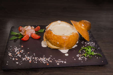 Fresh pea soup in a Bread Bowl, on a wooden board with salt and papper.の写真素材