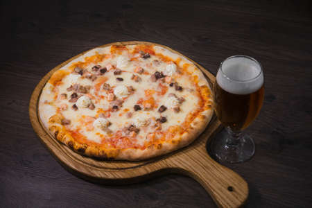 Hot piece of pizza with melted cheese on a rustic wooden table and beer.の写真素材