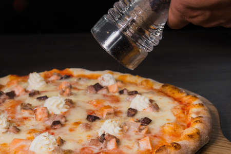 Hot piece of pizza with melted cheese on a rustic wooden table.の写真素材