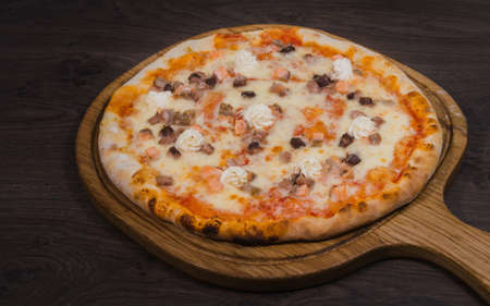 Hot piece of pizza with melted cheese on a rustic wooden table.の写真素材