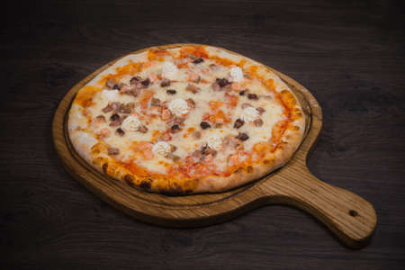 Hot piece of pizza with melted cheese on a rustic wooden table.の写真素材