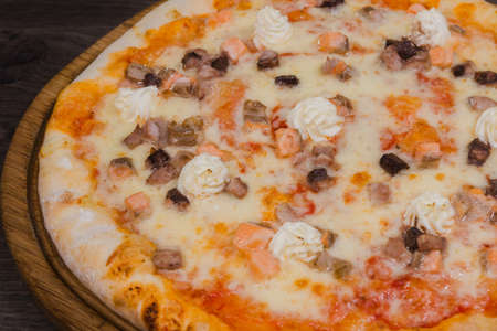 Hot piece of pizza with melted cheese on a rustic wooden table.の写真素材