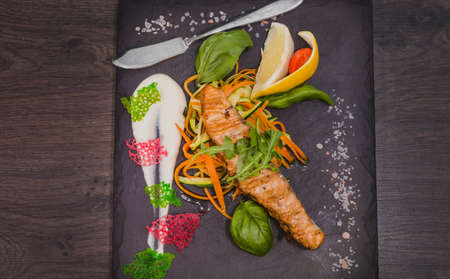 Salmon steak with lemon greens and sauce on stone with salt.の写真素材
